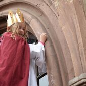 Carla aus der Gemeinde St. Godehard schreibt den Segen an die Tür des Alten Rathauses in Göttingen.